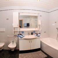 Helles Badezimmer mit Badewanne, separater Duschkabine, Waschbecken mit Spiegelschrank sowie WC und Bidet.