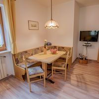 Helle Essecke mit Holztisch, Eckbank, zwei Stühlen und einem Fernseher an der Wand.