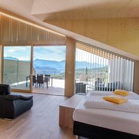 Modernes Schlafzimmer mit Holzwänden, großem Bett und Balkon mit Blick auf die Berge.