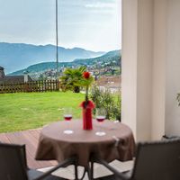 Terrasse mit gedecktem Tisch und Blick auf ein Dorf im grünen Bergtal.