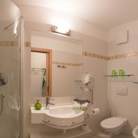 Helles Badezimmer mit Dusche, Waschbecken, Spiegel, Toilette und Bidet.